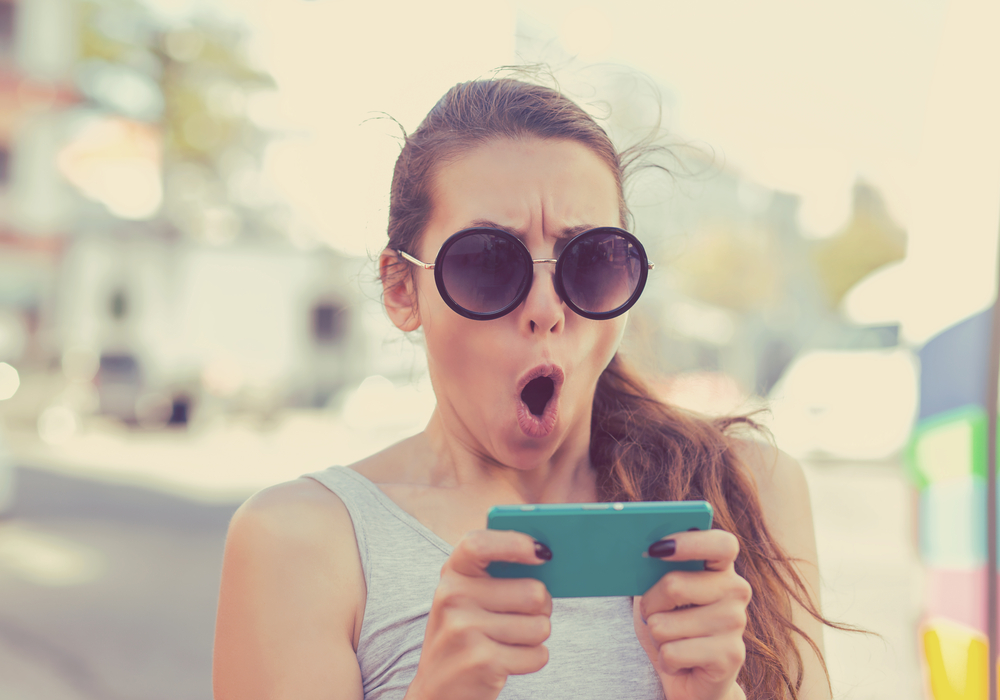 a woman looking surprised at her phone